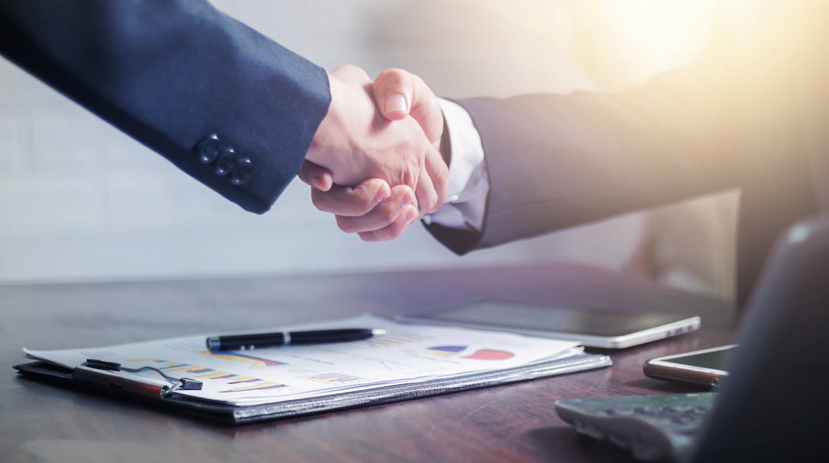 Professional handshake over business charts in a banking meeting
