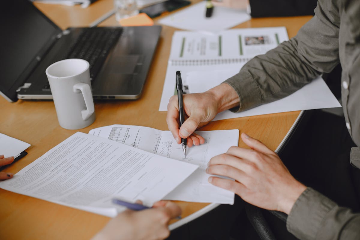 Professionals signing compliance documents at a business meeting